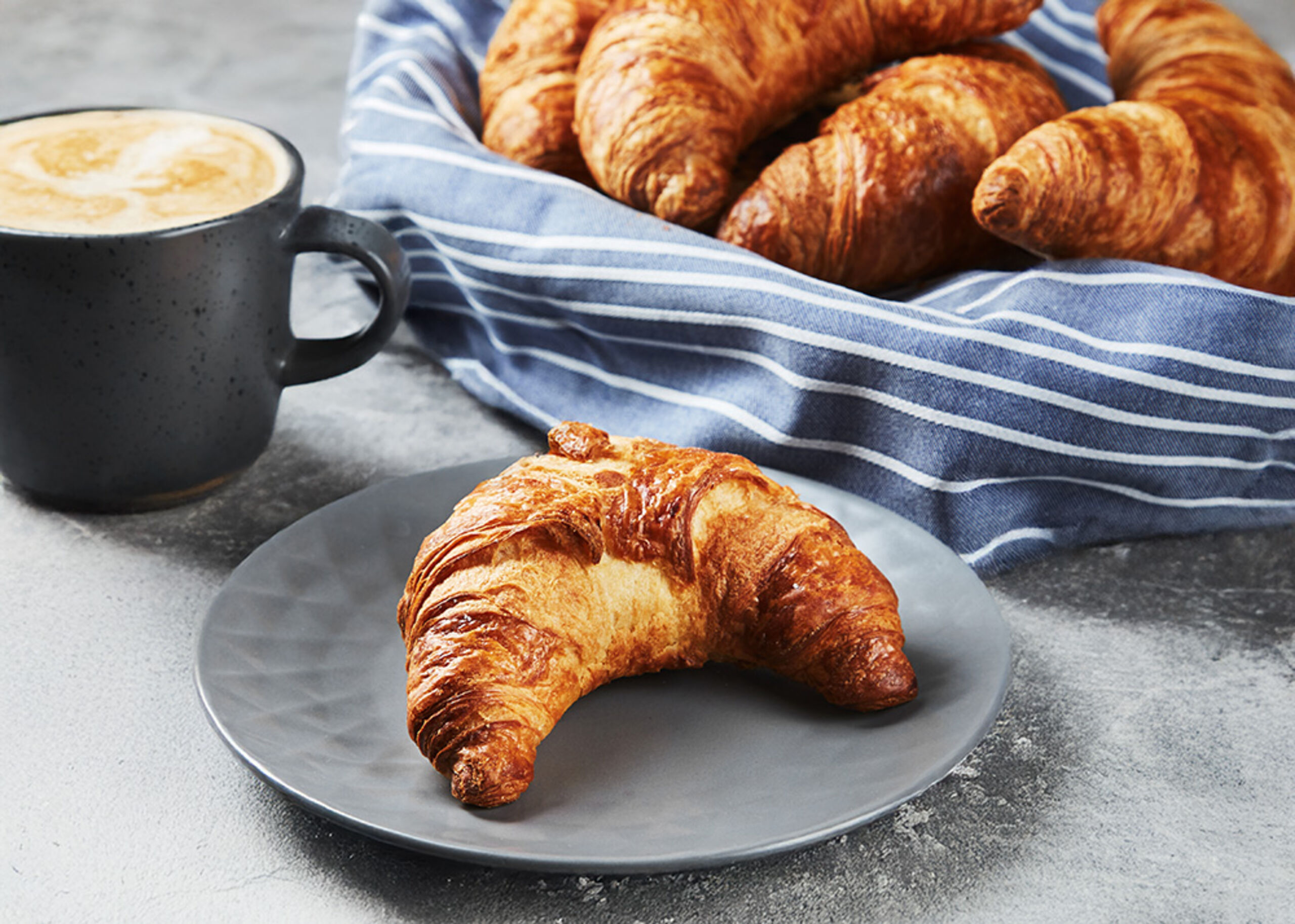 17901500 Schulstad Medium All Butter Curved Croissants on Plate & in Basket